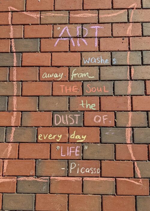 Brick with words in many colors of chalk: "Art washes away from the soul the dust of every day life. --Picasso"