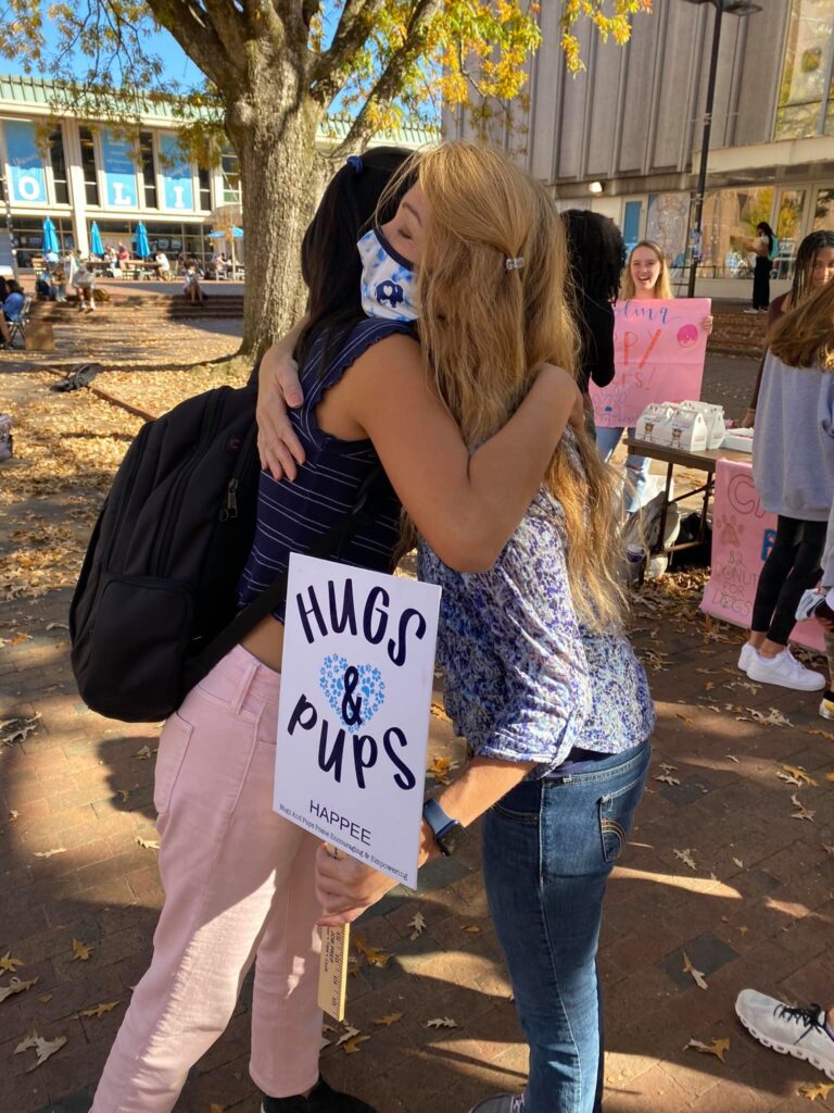 HAPPEE adult volunteer hugging a UNC student